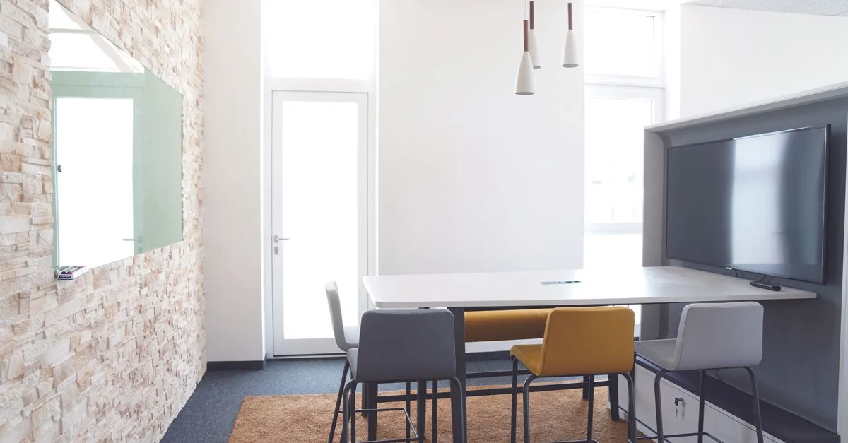 Une salle de réunion élégante et minimaliste avec une décoration moderne et un grand espace télévisuel, parfait pour les présentations.