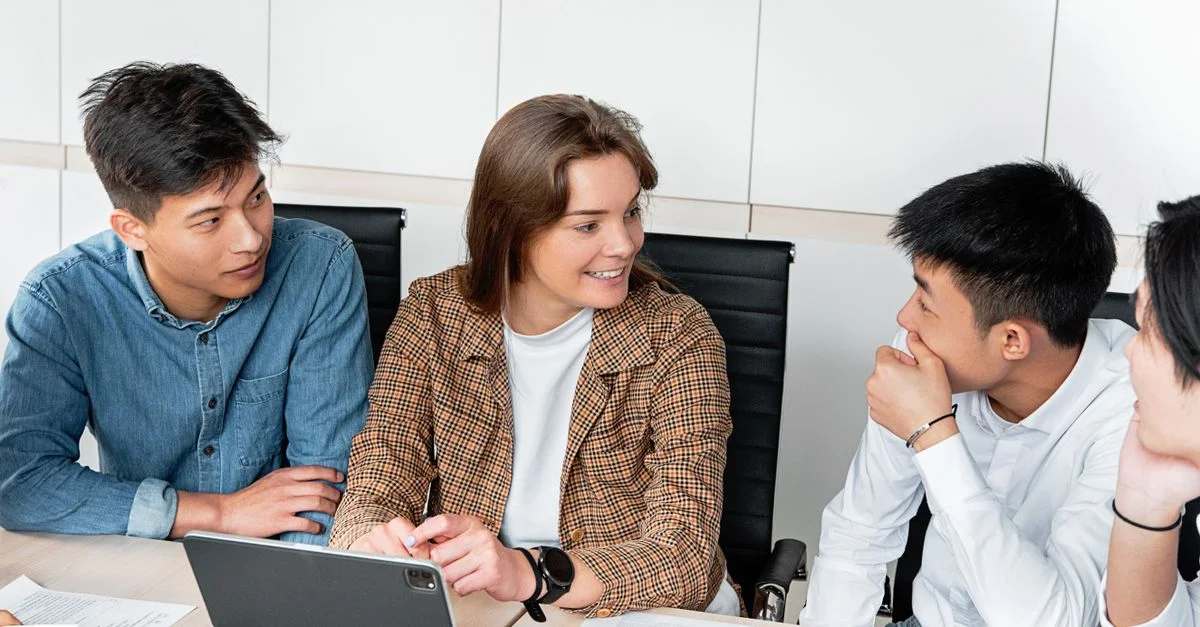 Un groupe de jeunes professionnels engagés dans une discussion collaborative autour de la table de bureau.