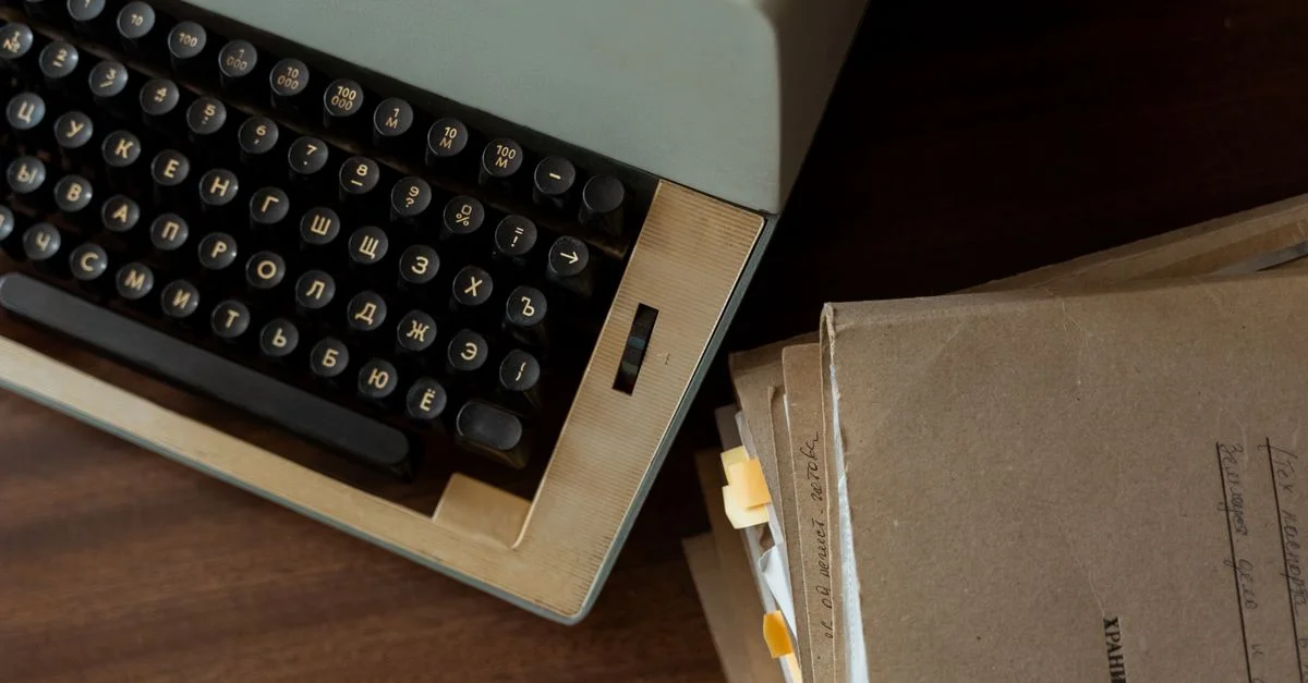 Une machine à écrire vintage classique à côté de documents empilés en papier brun sur un bureau en bois.