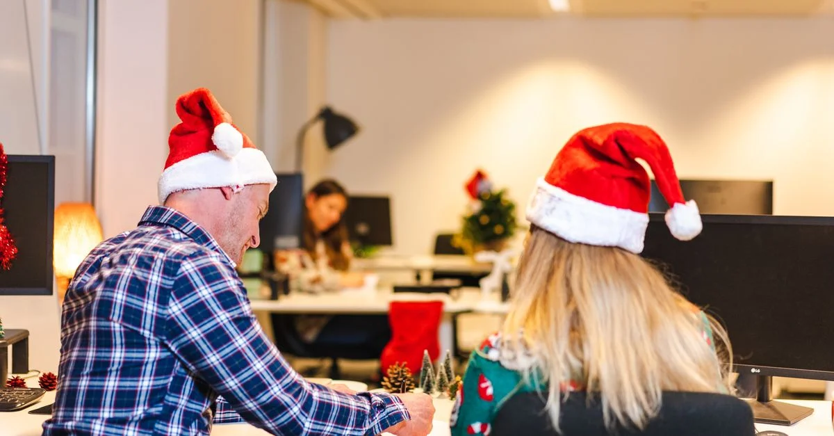 Collègues en chapeaux de Noël collaborant dans un bureau festif pendant la période de Noël.