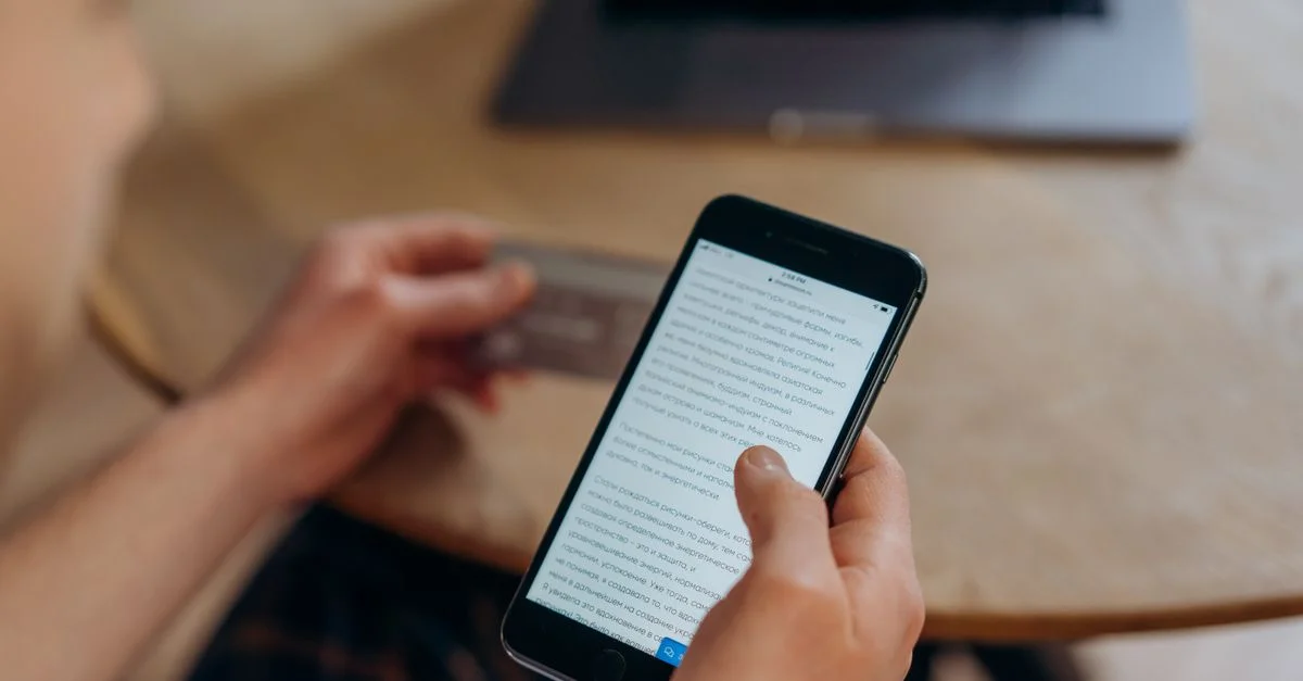 Gros plan sur une personne tenant un smartphone et une carte de crédit. Idéal pour des concepts de shopping en ligne.