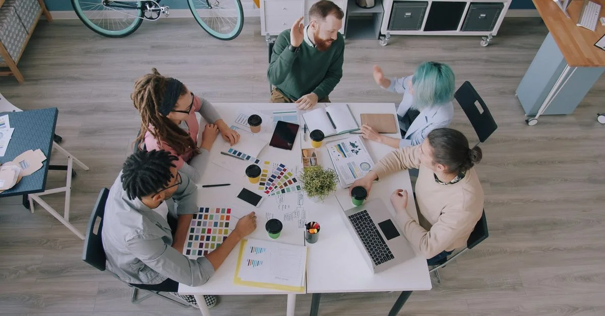 Vue de dessus d'une équipe créative aux profils variés collaborant dans un espace de travail équipé de technologies et de graphiques.