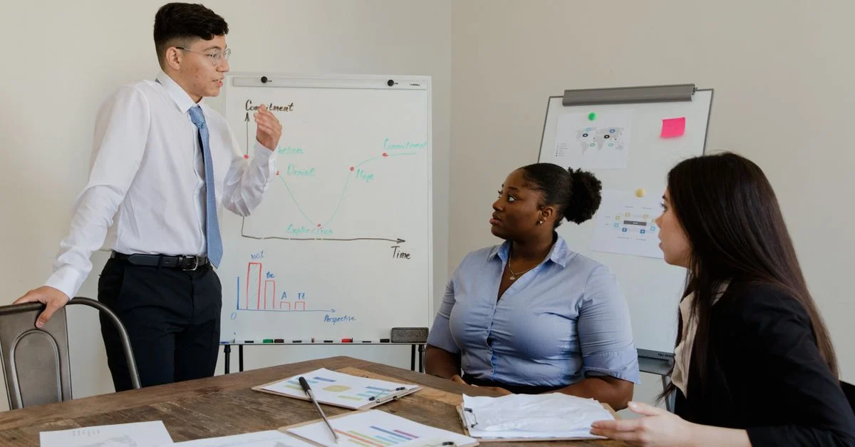 Un groupe diversifié de collègues participant à une réunion d'affaires avec une présentation sur tableau blanc et des documents.