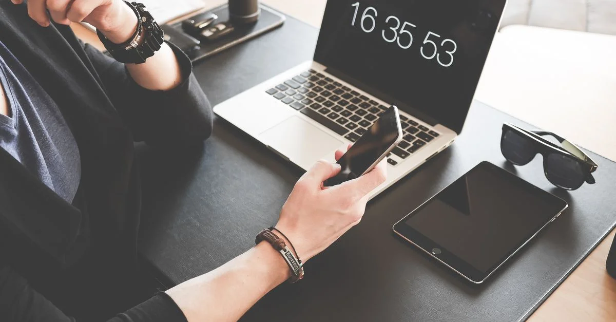 Un espace de travail moderne avec un ordinateur portable, un smartphone, une tablette et des lunettes de soleil, illustrant la connectivité numérique.