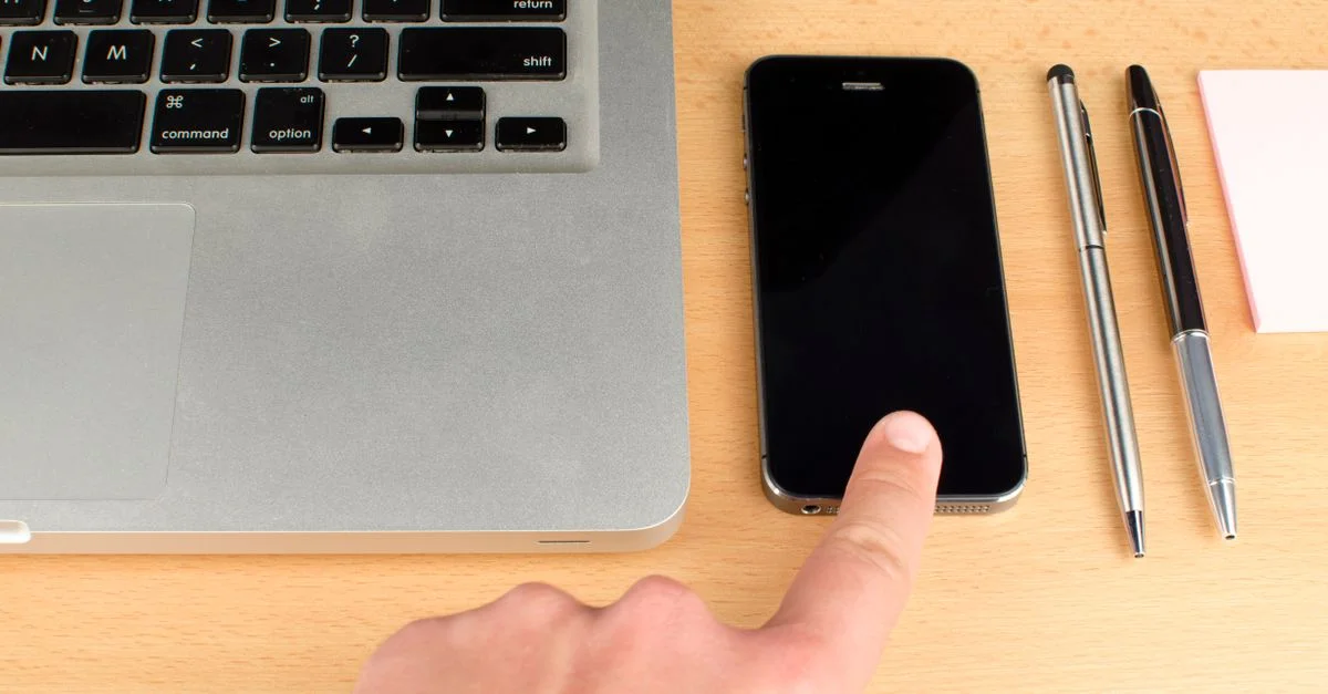 Gros plan d'un espace de travail avec un ordinateur portable et un smartphone sur un bureau en bois.