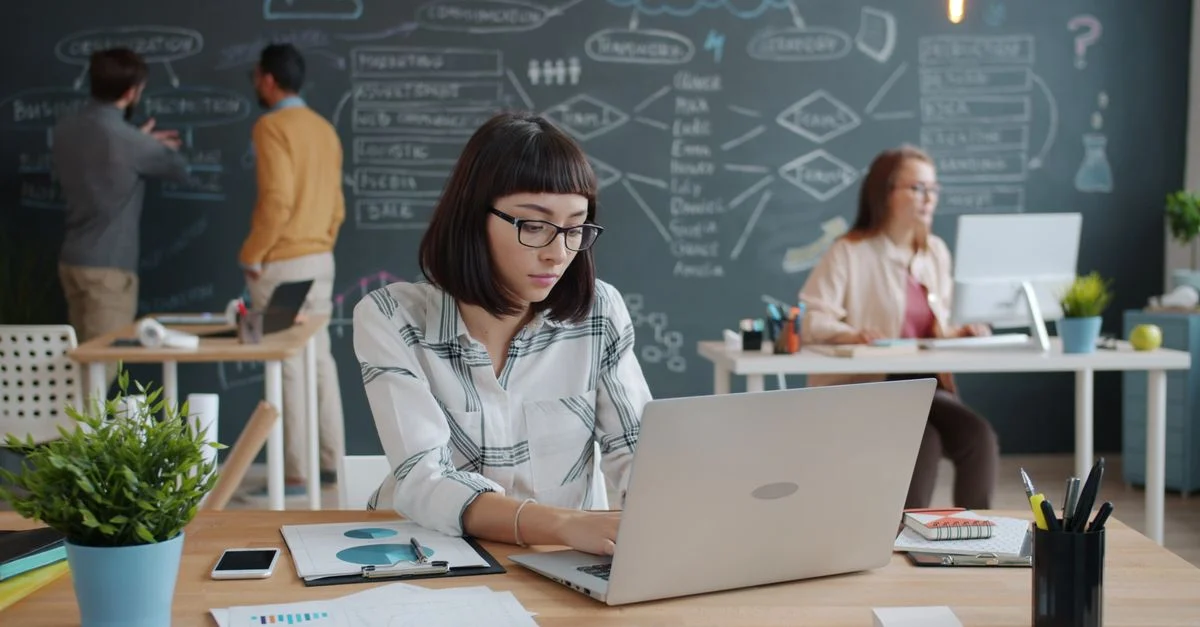Une équipe de jeunes professionnels travaille dans un bureau moderne et participe à une séance de brainstorming au tableau noir.