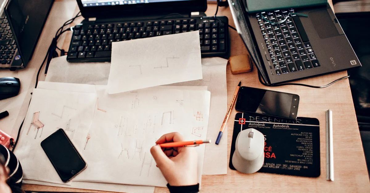 Vue de dessus d'un espace de travail avec des esquisses, des ordinateurs portables et des outils de dessin.