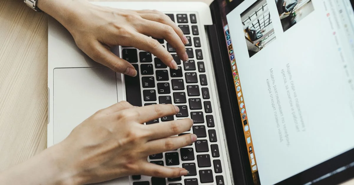 Gros plan sur des mains tapant sur le clavier d'un ordinateur portable dans un bureau.