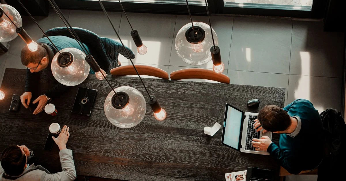 Prise de vue aérienne de professionnels utilisant des ordinateurs portables et savourant un café dans un cadre de café moderne.