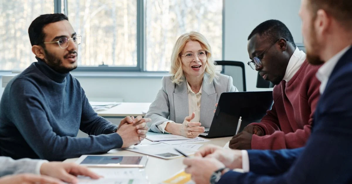 Groupe de professionnels en réunion discutant du travail d'équipe dans un bureau.