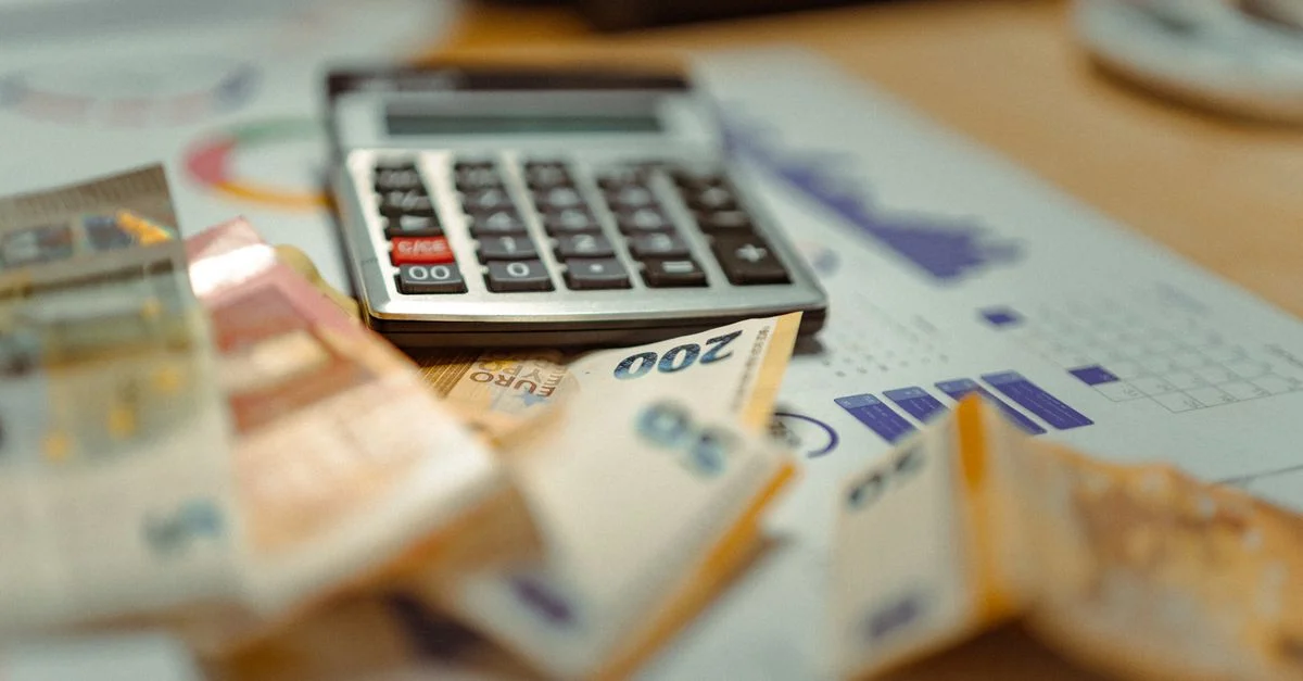 Billets en euros et calculatrice sur des documents financiers, axé sur la planification budgétaire des entreprises.