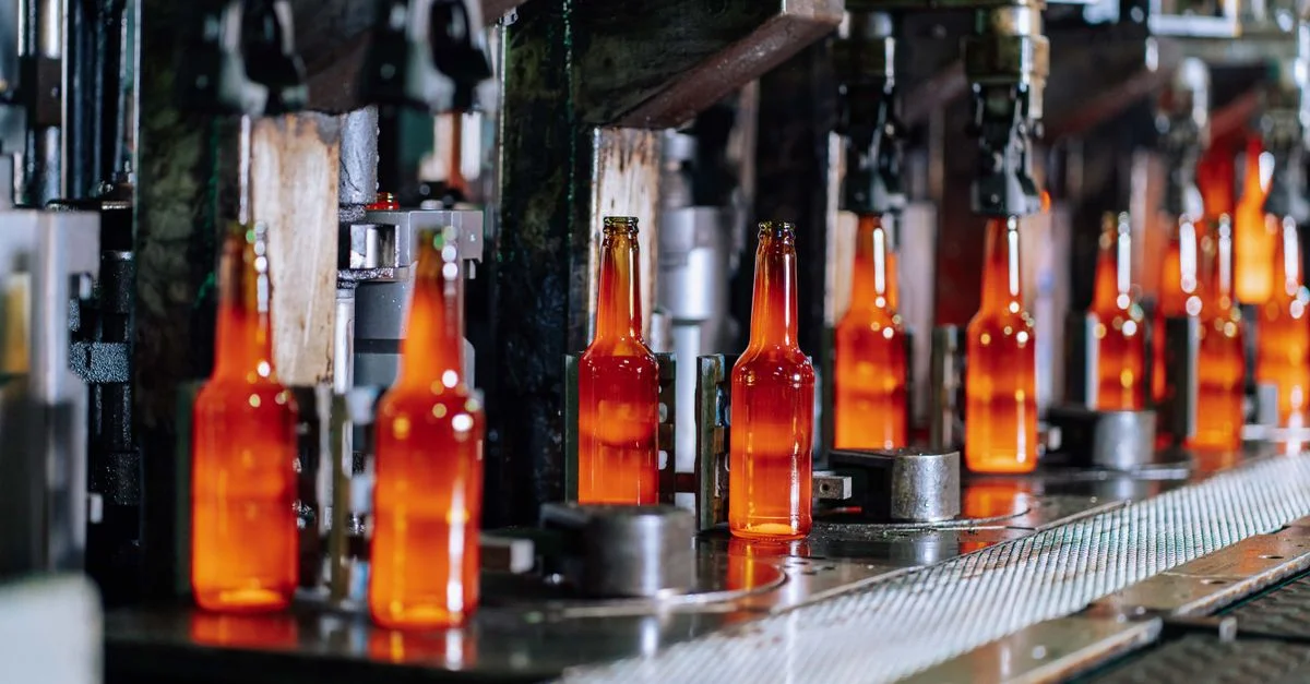 Bouteilles en verre sur une ligne de production dans une usine de verre moderne, mettant en avant l'automatisation industrielle.