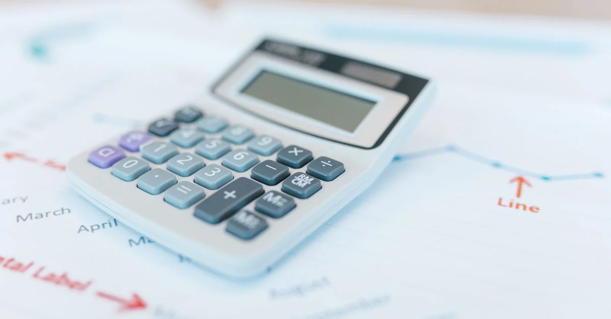 Gros plan sur une calculatrice sur des documents financiers avec des graphiques et des analyses.